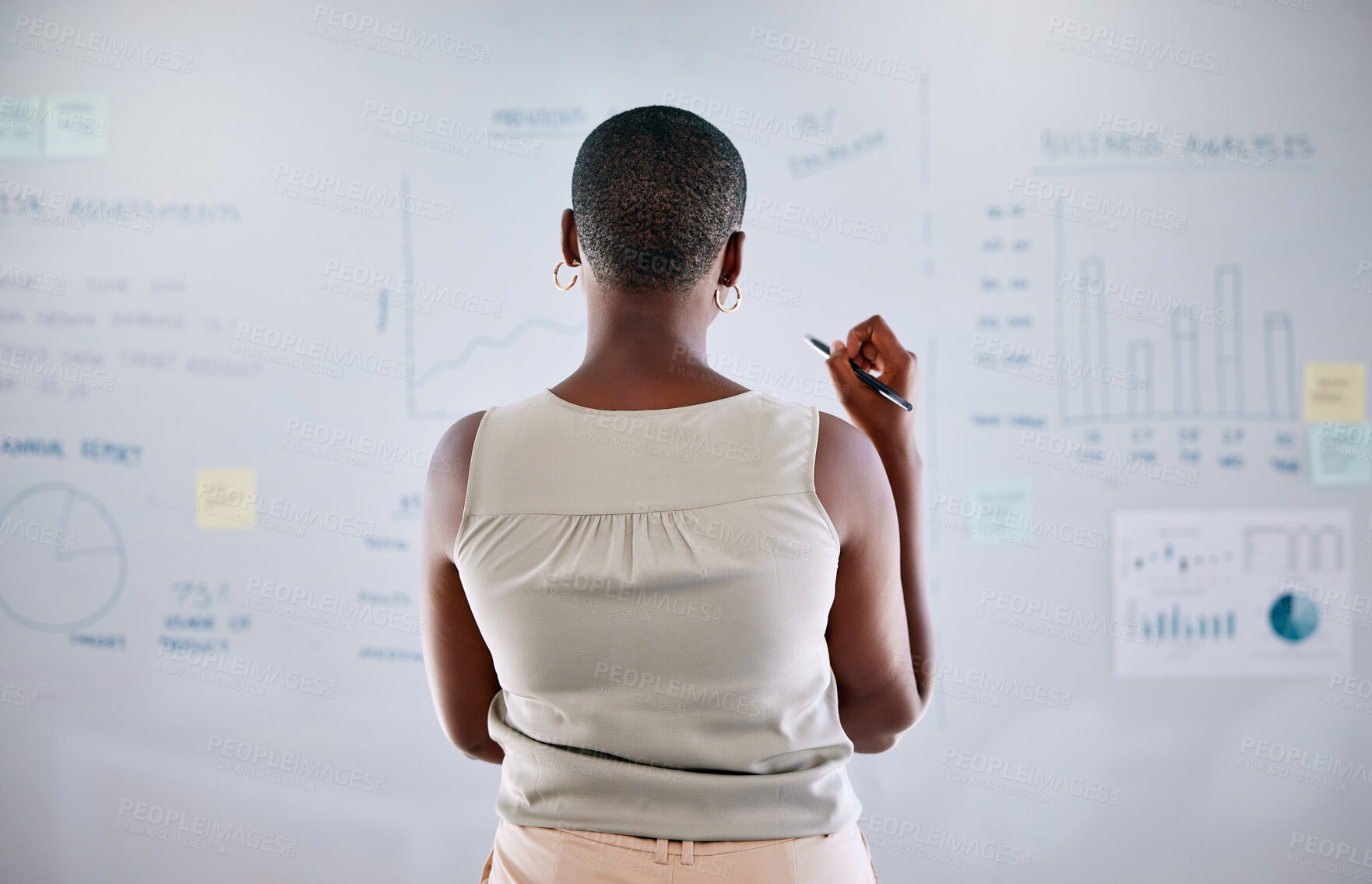 Buy stock photo Black female looking at analytics, seo research, and statistics on a whiteboard strategizing the next move for her startup business. A motivated modern woman with a clear vision thinking and innovating