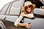 One beautiful caucasian woman hanging out the window of a car while taking a roadtrip. Attractive young female hipster with tattoos on her arm, wearing a hat and sunglasses and taking a drive in a car