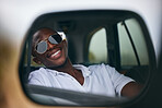 One African American man looking in the car mirror while taking a roadtrip. Smiling black man enjoying the weekend and taking a trip in a vehicle while wearing sunglasses 