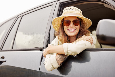 Buy stock photo Portrait of One beautiful young brunette caucasian woman hanging out the window of a car while taking a road trip, travelling to her destination. Attractive young female hipster with tattoos on her arm smiling and looking relaxed, wearing a hat and sunglasses and taking a drive in a car to a vacation on a sunny day