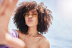 Portrait of young trendy beautiful mixed race woman with an afro smiling and posing for a selfie outside. Hispanic woman wearing sunglasses looking happy.Fashionable African American woman in the city