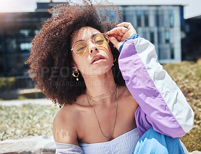 Young stylish mixed race woman with curly natural afro hair wearing trendy sunglasses and colourful vintage jacket. One female only looking cool and confident. Fashionable hispanic woman in the city