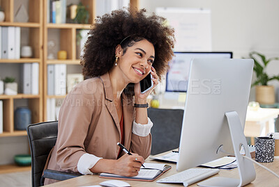 One young mixed race american businesswoman with an afro talking to clients with a cellphone and on a computer. Smiling hispanic creative professional networking and planning while using technology