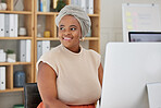 Young african american businesswoman with a headscarf sitting alone in an office and thinking while browsing the internet on a computer. Ambitious black creative planning ideas and emailing clients