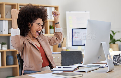 One mixed race African american businesswoman with an afro expressing joy while celebrating a win at her office job. Hispanic woman looking successful while using a desktop. Happy female screaming yes