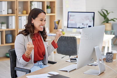 One mixed race asian businesswoman expressing joy while celebrating a win at her office job. Chinese woman looking successful while using a desktop. Happy female screaming yes and holding a fist