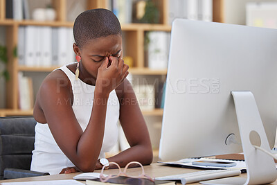 Bored young businesswoman sitting at her desk in front of her computer looking annoyed and suffering from a headache problem. Business professional sitting at desk looking, upset, depressed and sad. Serious businesswoman looking tired and suffering from b