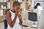 One young african american businesswoman sitting at her desk feeling unwell and blowing her nose with a tissue due to her sinus and flu. Black woman feeling sick and suffering from fever at her job while sitting in front of her computer