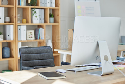 A desktop computer and keyboard standing on a table inside of a quiet empty work office during the day. A Managers empty office during a lunch break at office during business hours with a chair and a closed book on the table.