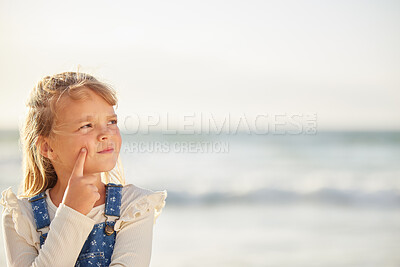 Buy stock photo One adorable little girl thinking of ideas while standing on a beach outdoors. A cute young kid looking thoughtful while outside with the sea in the background. The mind and imagination on a child