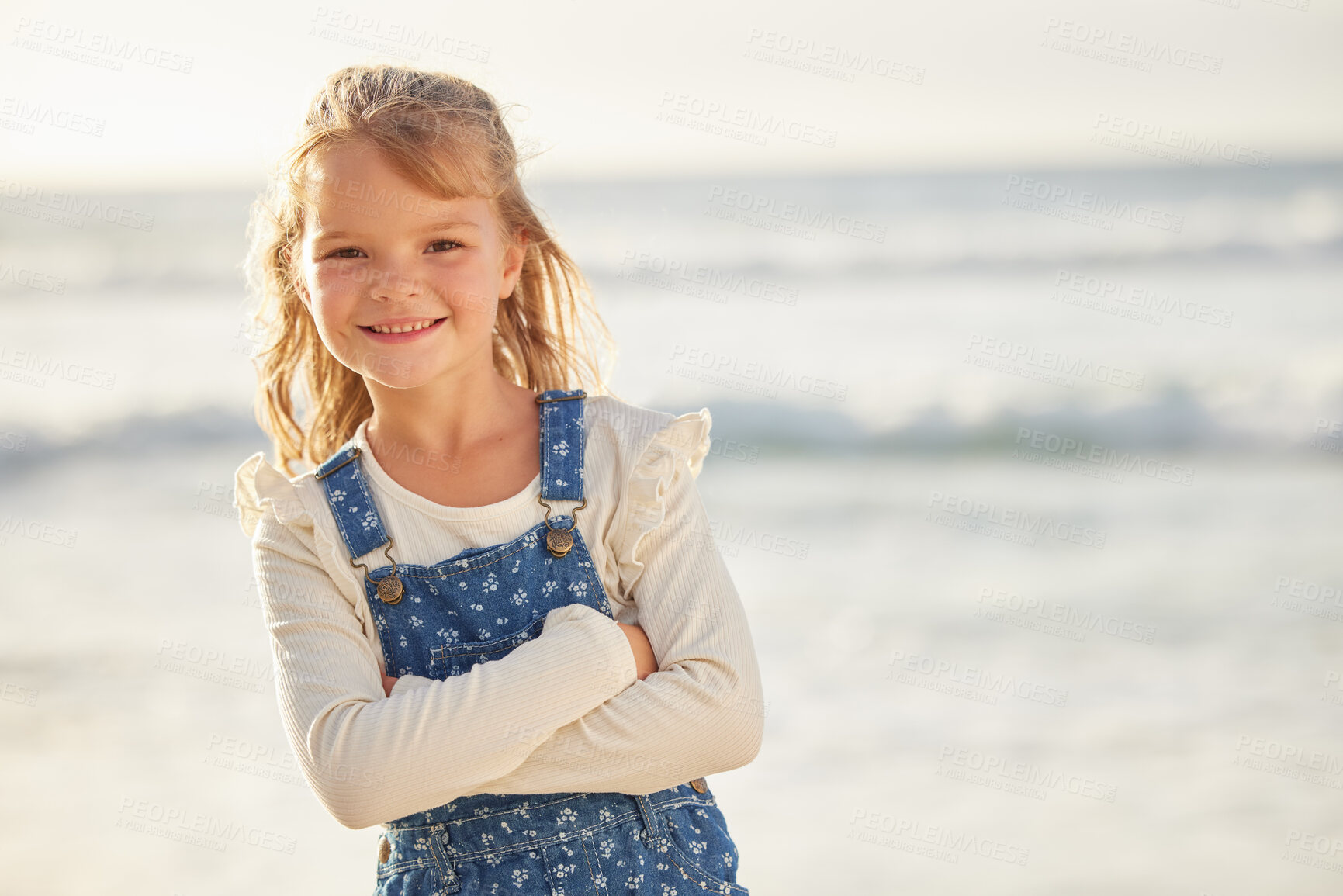 Buy stock photo Happy little girl standing with her arms crossed during summer at the beach. Cheerful caucasian small child enjoying a day at the beach, posing. Blond girl enjoying a sunny summer day by the ocean
