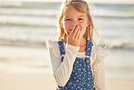 Close up portrait on a little young caucasian brunette girl making a shocked gesture with her hand while smiling and standing alone outside at the beach on a sunny summer day. Young girl looking surprised while on vacation , innocent and happy