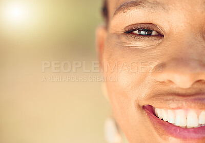 Closeup portrait of a beautiful young African American woman face. Smiling black female showing her healthy teeth and perfect dental and oral hygiene while outside in the city enjoying fresh air.