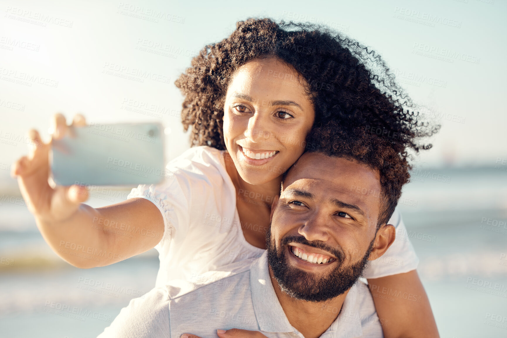 Buy stock photo Couple, piggyback and selfie at beach, summer sunshine and happy for travel, blog and post on web. Man, woman and smile for photography on romantic vacation, profile picture and social network app