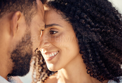 Closeup of an young affectionate mixed race couple standing on the beach and smiling during sunset outdoors. Hispanic couple showing love and affection on a romantic date at the beach