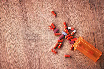 An open orange bottle of brightly coloured pills spilled onto a wooden table. Vitamin supplements are a great way to stay healthy. Chronic or prescription medication is usually covered by medical aid