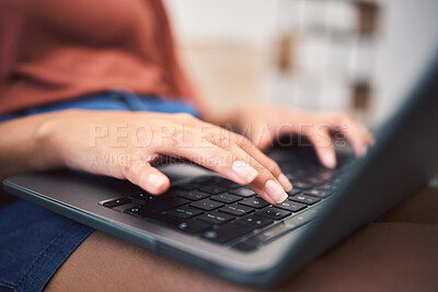 Closeup shot of an unrecognizable mixed race woman using a laptop while doing remote work from the couch. Young female doing freelance work while using the internet for research and sending an email
