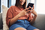 Close up of female hand's using smartphone to browse the internet, using mobile app or messaging on social network while sitting on the couch at home