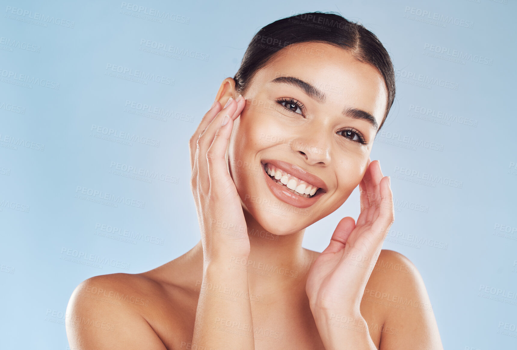 Buy stock photo Closeup face beautiful young mixed race woman. Attractive female touching her face in studio isolated against a blue background. A skincare regime to keep your skin soft, smooth, glowing and healthy