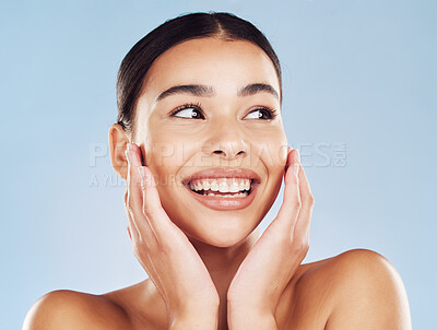 Closeup face beautiful young mixed race woman. Attractive female touching her face in studio isolated against a blue background. A skincare regime to keep your skin soft, smooth, glowing and healthy