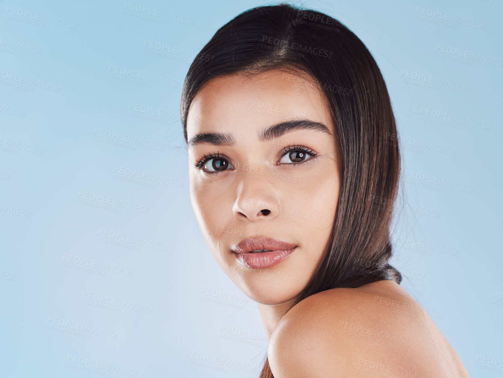 Buy stock photo Portrait of one beautiful young hispanic woman with healthy skin and sleek hair posing against a blue studio background. Mixed race model with flawless complexion and natural beauty
