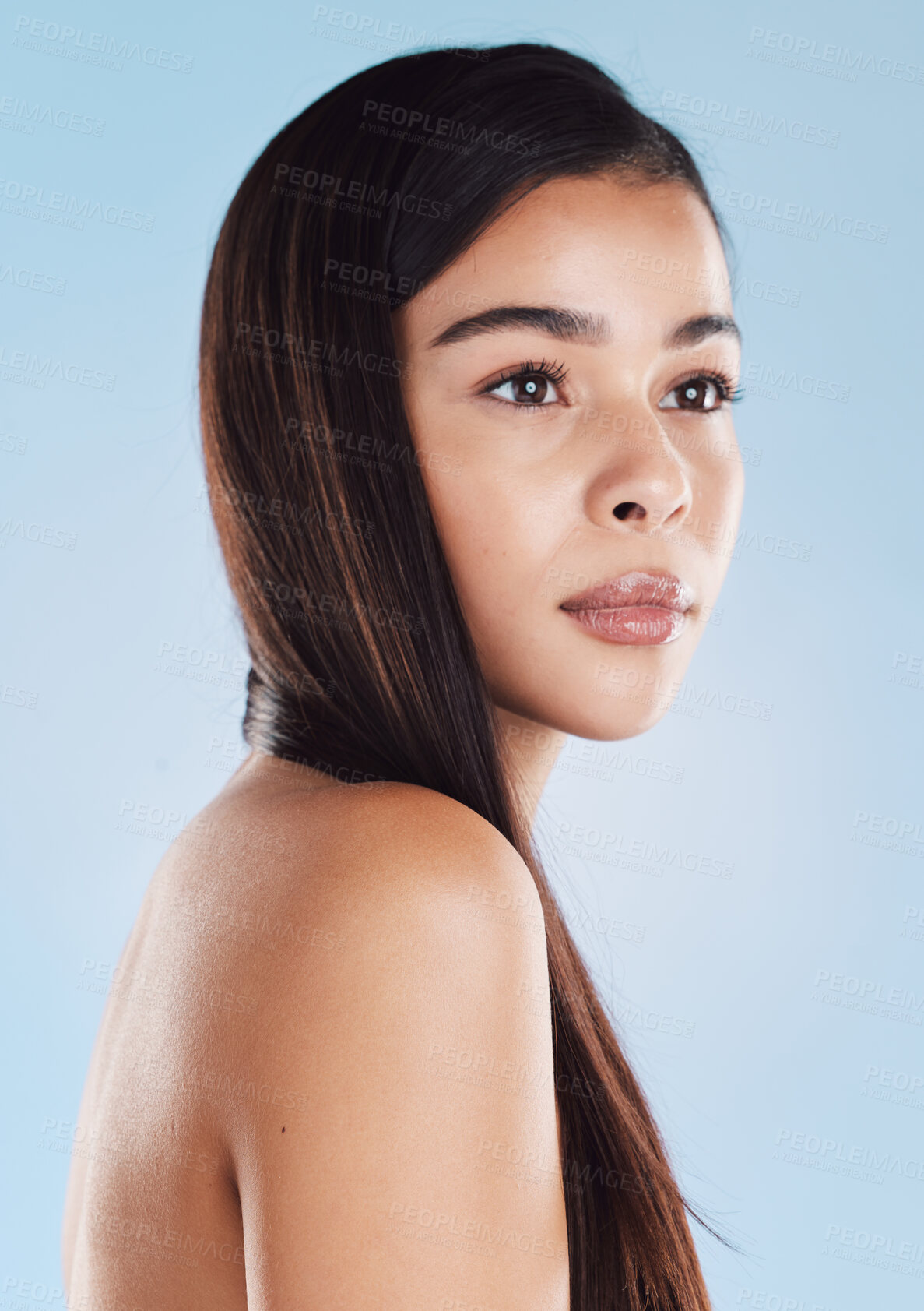 Buy stock photo One beautiful young hispanic woman with healthy skin and sleek long hair posing against a blue studio background. Mixed race model with flawless complexion and natural beauty