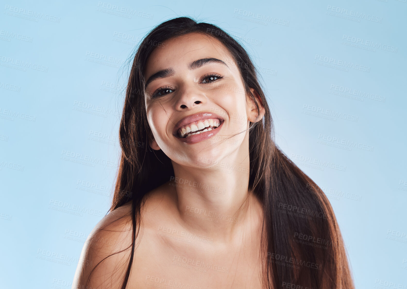 Buy stock photo Portrait of one beautiful young hispanic woman with healthy skin and sleek long hair smiling against a blue studio background. Happy mixed race model with flawless complexion and natural beauty