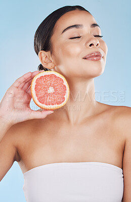 Buy stock photo Grapefruit, woman skincare and wellness fruit for face grooming, wellness and diet health on a blue background in studio. Happy, smile and beauty brazilian model with vitamin c food product in hands 