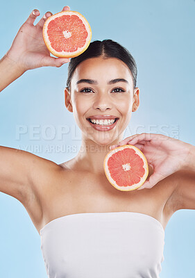 Buy stock photo Wellness, health and beauty with woman and grapefruit with a smile against a blue background studio. Skincare, nutrition and confident portrait of a young wellbeing female holding fruit 