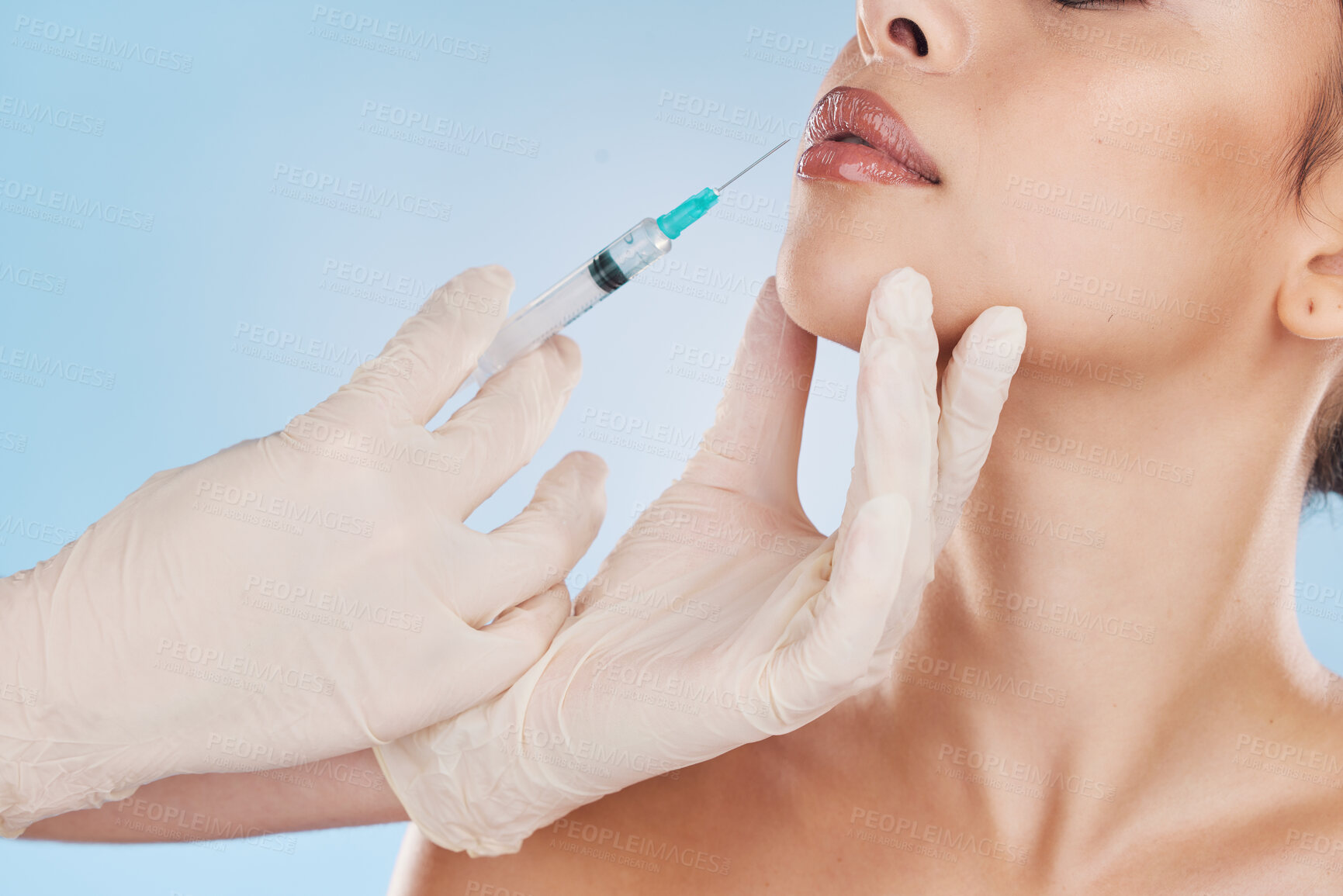 Buy stock photo Botox, plastic surgery and filler with the lips of woman getting an injection with a syringe from the hands of a surgeon in gloves. Mouth, face and needle for beauty in studio on a blue background