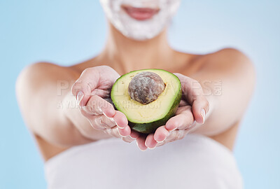 Buy stock photo Hands holding an avocado fruit for skincare, beauty and cosmetic wellness on a blue mockup studio background. Woman with face mask for health, skin and body care giving nutrition food for eating