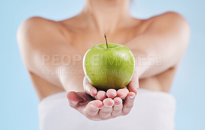 Buy stock photo Hands of woman, holding out healthy apple or health, wellness and food on a blue background. Beauty, care and nutrition of model or girl with ripe, juicy fruit and vitamins for a lifestyle diet.
