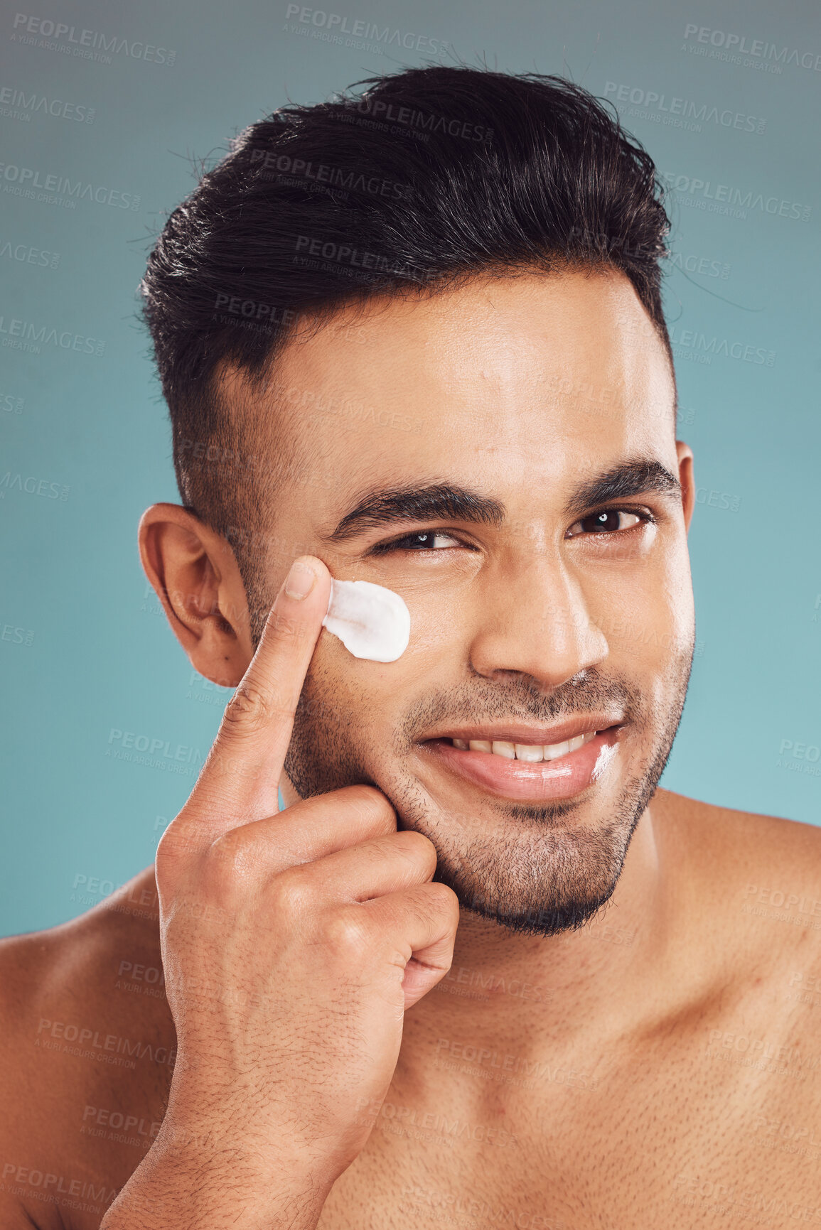 Buy stock photo Portrait, skincare and lotion with a man in studio on a gray background to apply antiaging facial treatment. Face, beauty and cream with a young male person indoor for wellness or aesthetic self care