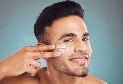 Buy stock photo Portrait, beauty and cream with a man on a gray background in studio to apply antiaging face treatment. Facial, skincare and lotion with a young male person indoor for wellness or aesthetic self care