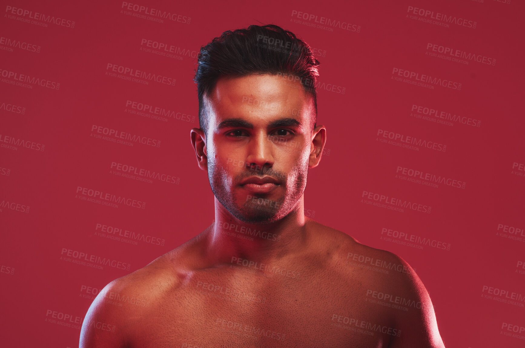 Buy stock photo Closeup portrait of bare chested athletic young man posing against a red background. Handsome young masculine hispanic man posing in the studio 