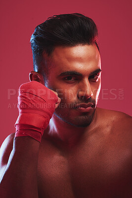 Buy stock photo Portrait of one fit and strong handsome mixed race kickboxer isolated against a red studio background and getting ready to fight. Hispanic man posing shirtless in a punching stance. Focused on target
