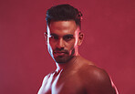 Closeup portrait of handsome athletic young man posing against a red background. Shirtless young masculine hispanic man posing in the studio 