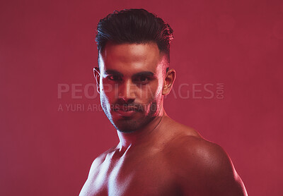 Buy stock photo One handsome young indian man posing topless against a red studio background. Serious masculine guy looking confident and charming with muscular bare body 