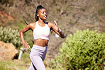 Fit and active African American woman running alone outside for a workout. Ambitious black athlete training and exercising for a marathon. Runner on nature trails jogging to increase cardio health