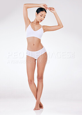 One beautiful young mixed race model posing seductively in underwear against a grey studio copyspace background. Confident hispanic woman showing her curvy shape and smooth hairless skin
