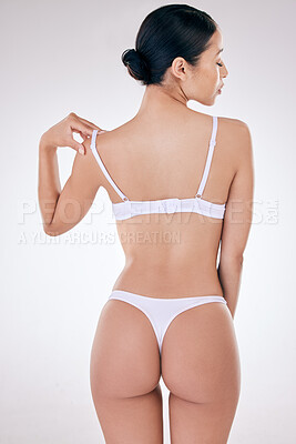 Rear view of one mixed race model posing in underwear against a white background studio. Hispanic female removing her bra while showing her thick shape in a studio