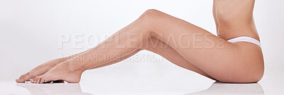 Closeup of unrecognizable woman posing in underwear against a white studio background. One female only feeling confident while showing her hairless, smooth legs after hair removal or epilation