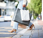 Unknown fashionable african american woman walking along the street in the city and carrying retail bags after shopping. High fashion black woman walking in high heels after buying gifts and clothes