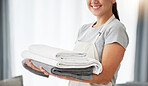 Hands of a woman holding a pile of laundry. Woman holding a stack of neat, folded laundry. Woman cleaning clothing at home. Woman carrying a pile of fresh, cleaned clothing at home