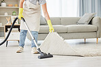 An unknown domestic worker lifting and cleaning under a carpet. One mixed race unrecognizable female using a vacuum cleaner under a mat to begin spring cleaning