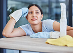 A mixed race domestic worker looking depressed while cleaning. One Hispanic female bored while cleaning her apartment