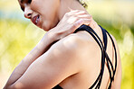 Closeup of one mixed race woman from behind holding neck shoulder while exercising outdoors. Female athlete suffering with painful injury from fractured joint and inflamed muscles during workout. Struggling with stiff body cramps causing discomfort