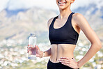 Closeup of one fit mixed race woman taking a rest break to drink water from bottle while exercising outdoors. Female athlete quenching thirst and cooling down after running and training workout