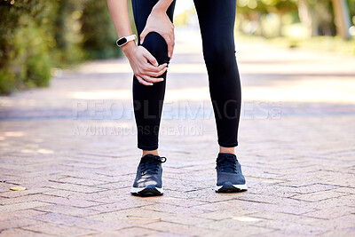Closeup of one mixed race woman holding her sore knee while exercising outdoors. Female athlete suffering with painful leg injury from fractured joint and inflamed muscles during workout. Struggling with stiff body cramps causing discomfort and strain