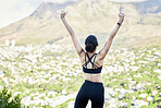 One mixed race woman from the back cheering with arms outstretched outdoors. Proud athlete celebrating victory and accomplishment after run or jog. Inspired and motivated to reach fitness and wellness goals